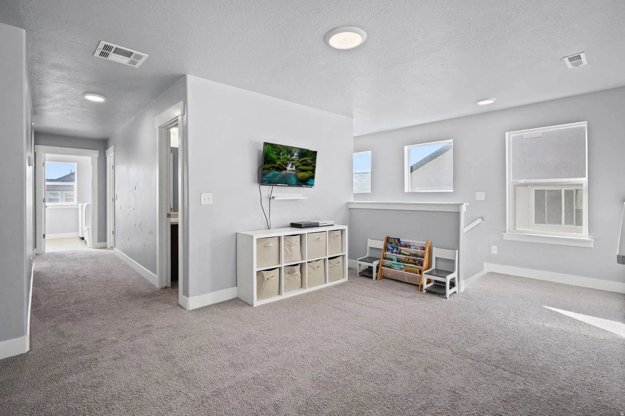 Loft upstairs with light carpet, a textured ceiling, and recessed lighting