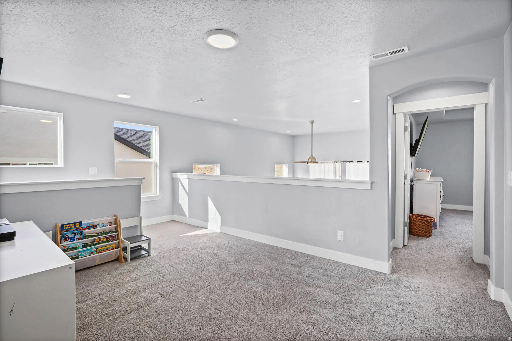 Loft upstairs with light colored carpet, a textured ceiling, and an upstairs landing