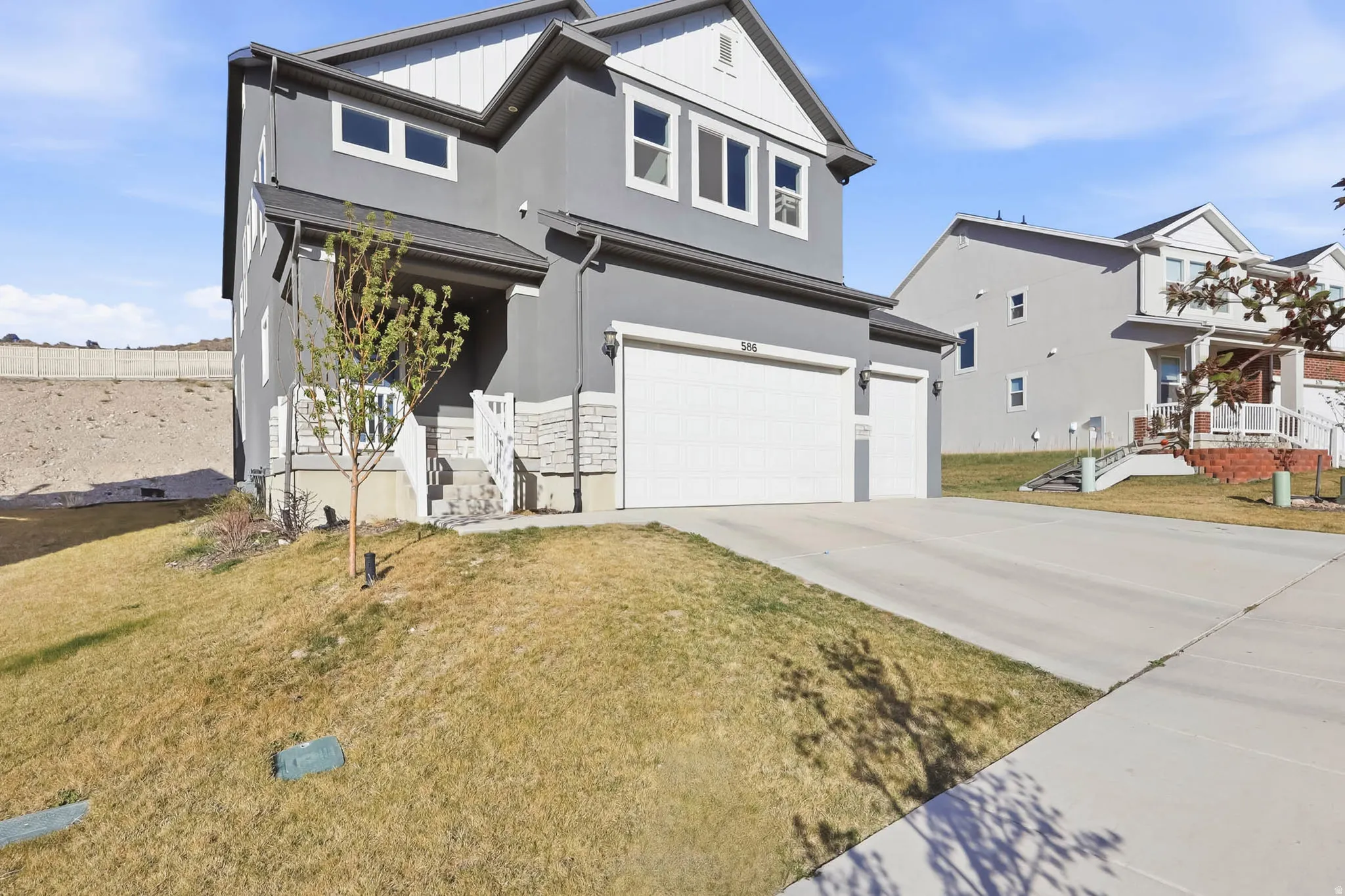 View of front of home with an attached 3-car garage, driveway, stucco siding, and a front yard