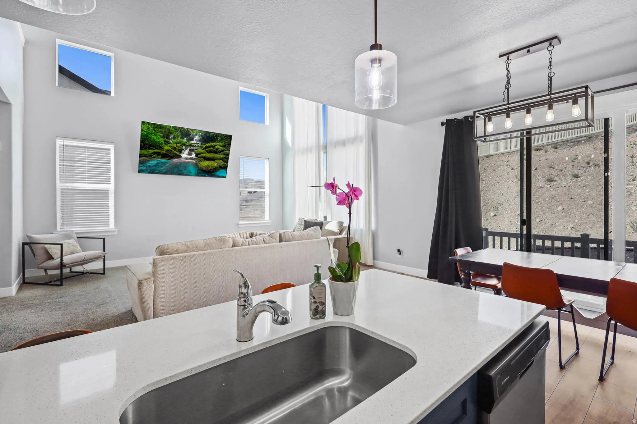 Kitchen featuring open floor plan, light stone countertops, a textured ceiling, dishwasher, and decorative light fixtures