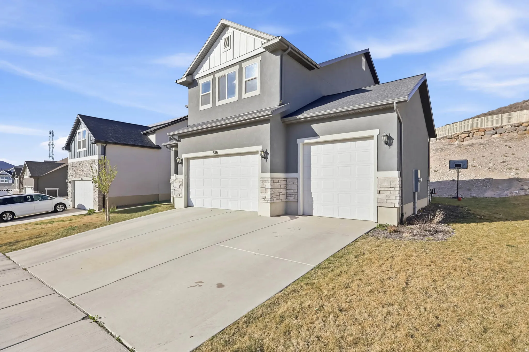 View of front of house with stone siding, concrete driveway, an attached 3-car garage, and stucco siding