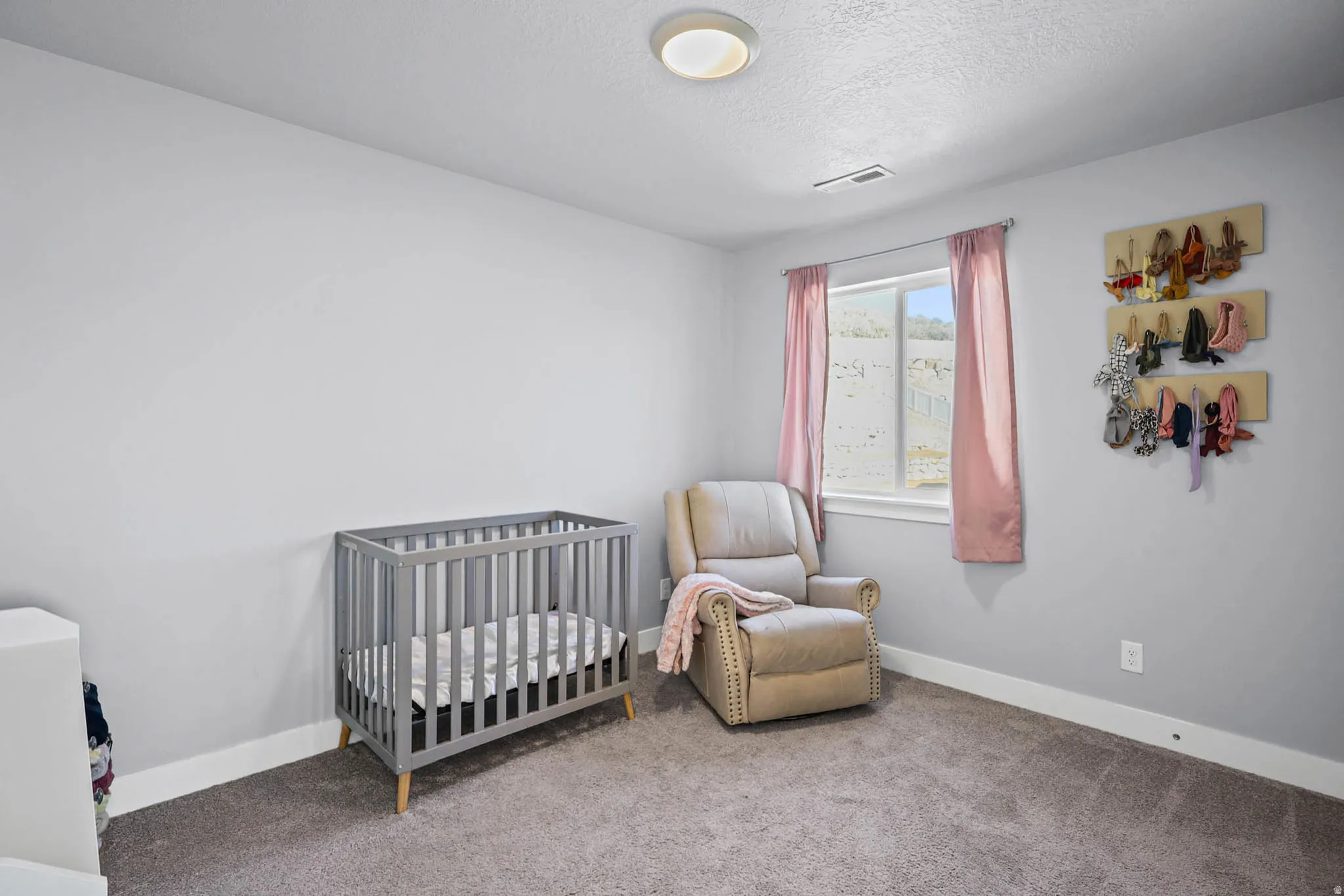 Carpeted bedroom featuring a nursery area and a textured ceiling