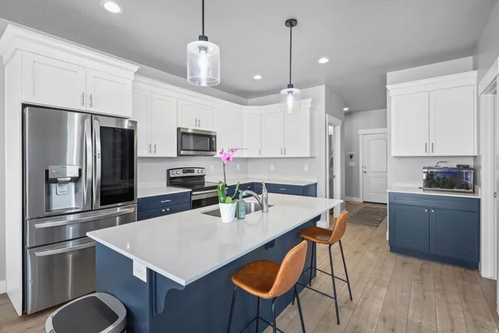 Kitchen featuring dual tone cabinetry, stainless steel appliances, a kitchen breakfast bar, an island with sink, and light wood finished floors