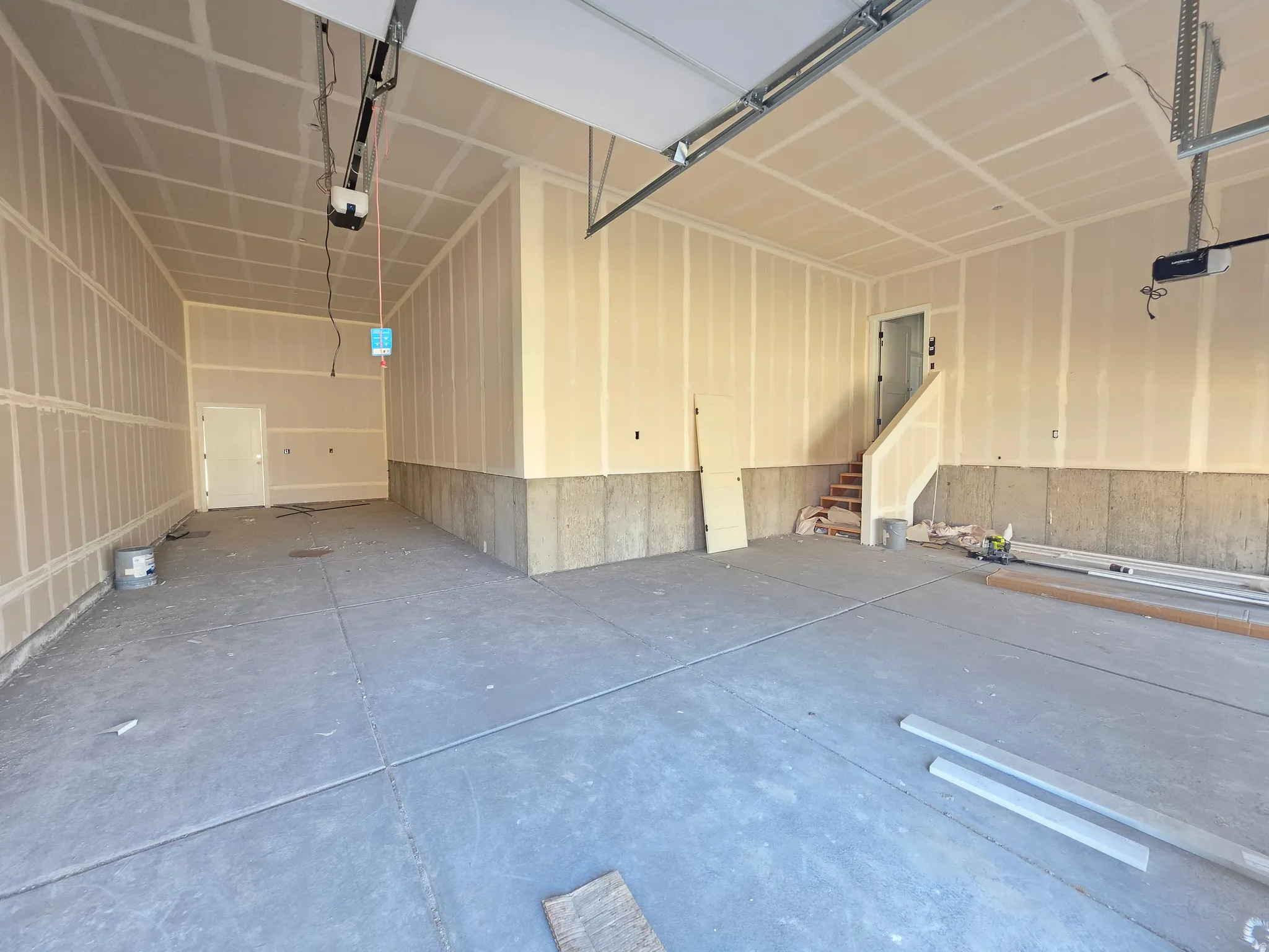 Spacious garage featuring a concrete floor, exposed drywall, and an interior access door