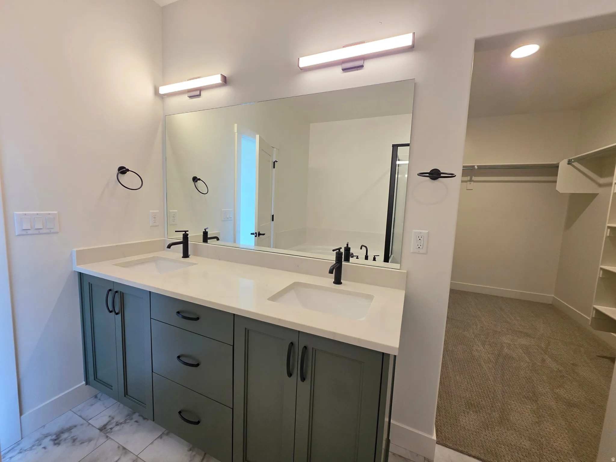 Dual vanity with light-colored countertops, matte black fixtures, and green cabinetry