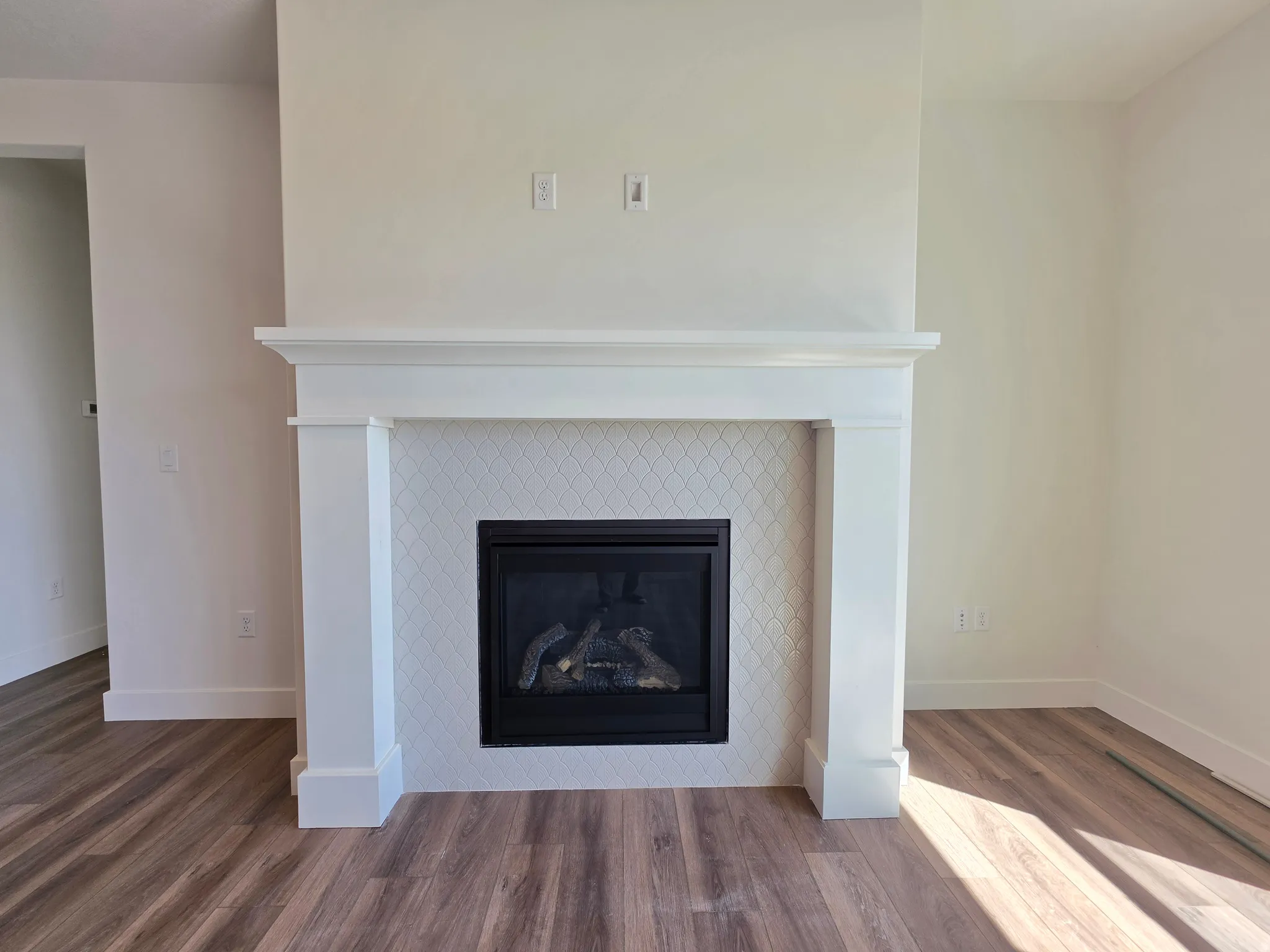 Fireplace featuring a white mantel, geometric tile surround, and a black insert