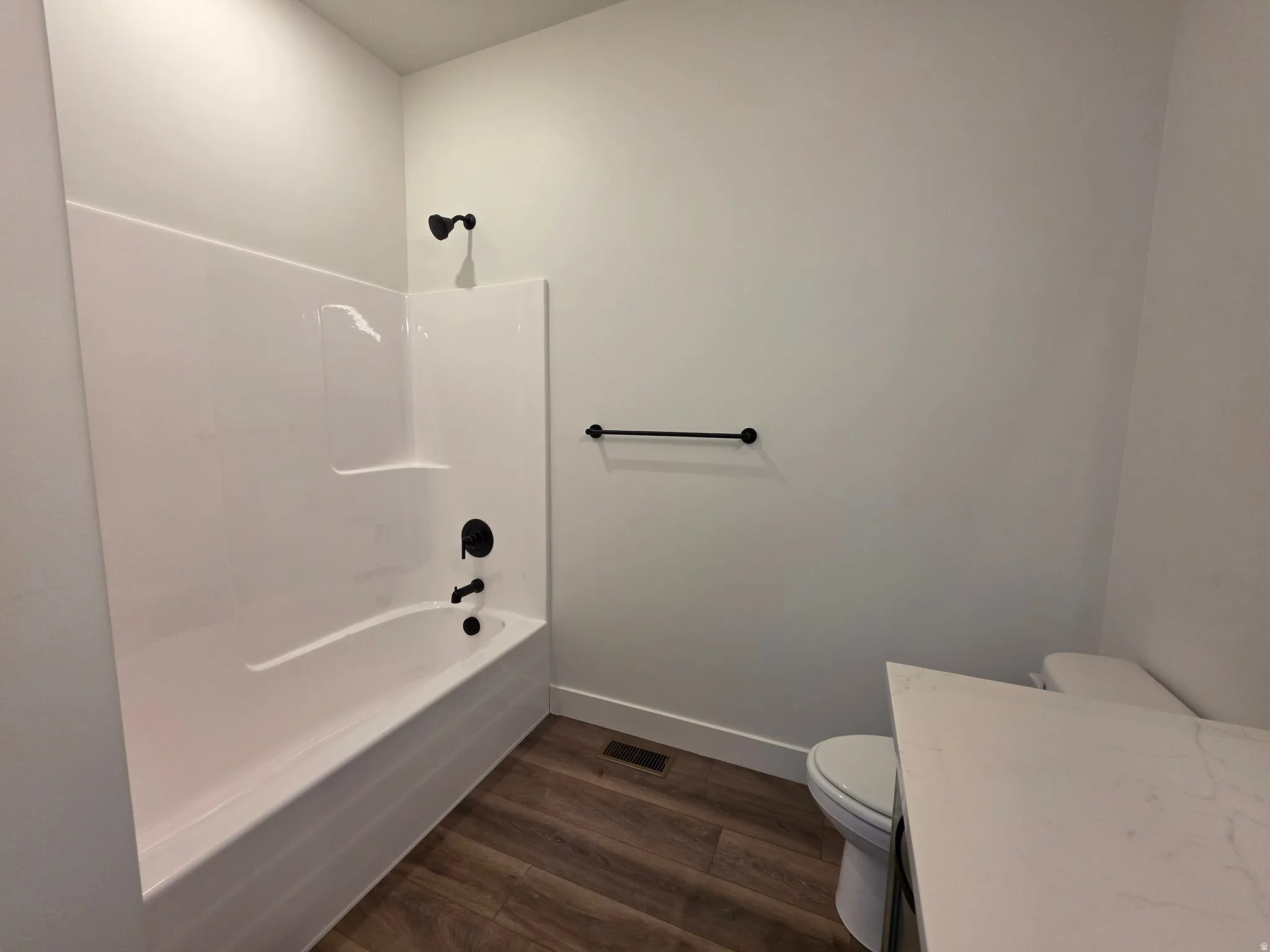 Bathroom featuring a white bathtub and shower surround with matte black fixtures