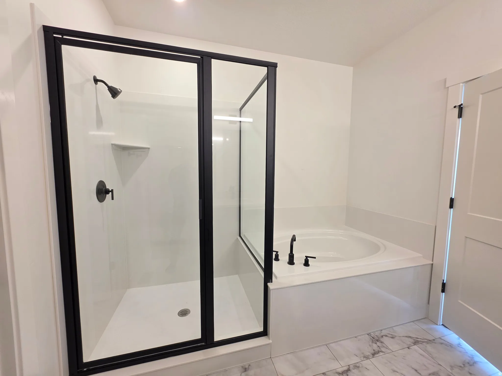 Contemporary bathroom featuring a walk-in shower with black-framed glass enclosure, built-in shower niche, and matte black fixtures