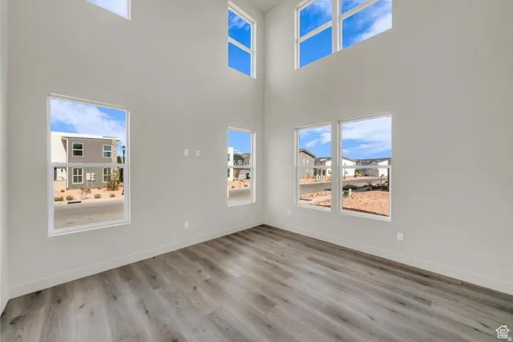 Unfurnished living room featuring light wood-style flooring, a high ceiling, and plenty of natural light