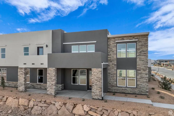 Modern home with stucco siding, a patio area, and stone siding