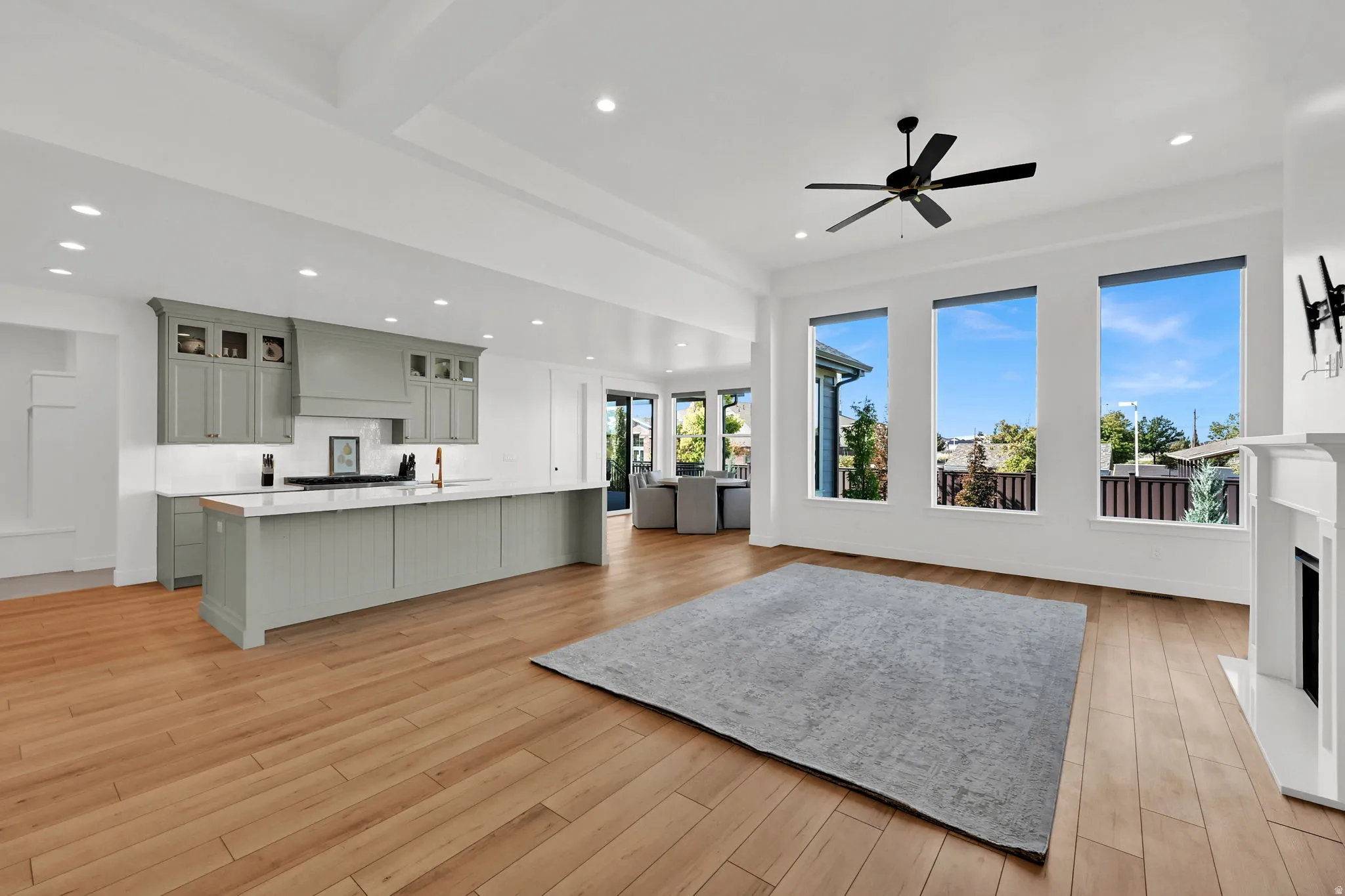 Kitchen with open floor plan, a large island with sink, glass insert cabinets, a fireplace, and light wood-style floors