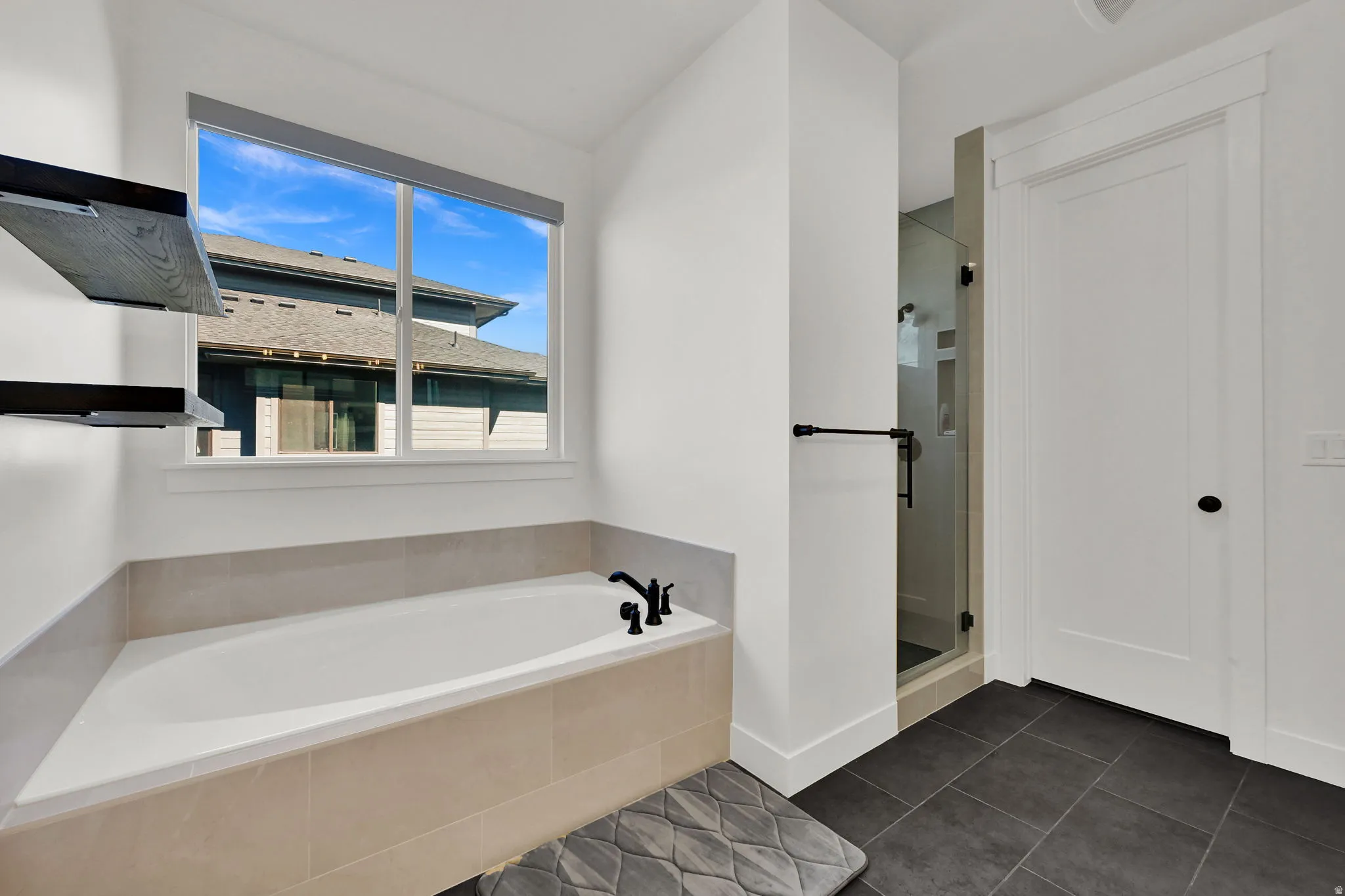 Full bath with a garden tub, a stall shower, and dark tile patterned floors