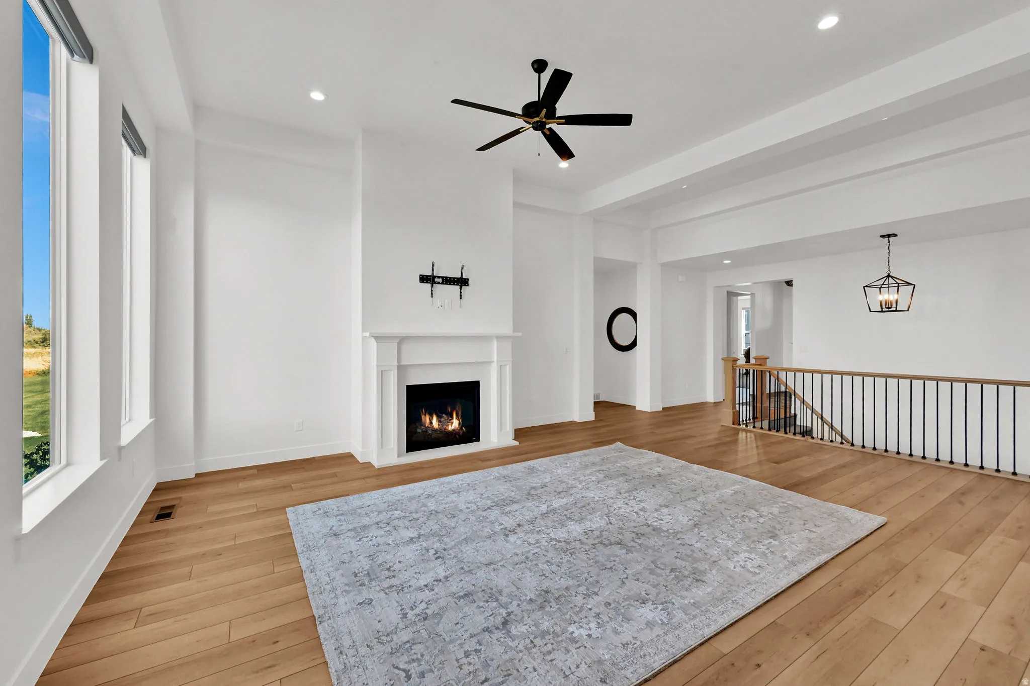 Living area with light wood-style floors, a ceiling fan, a warm lit fireplace, and recessed lighting