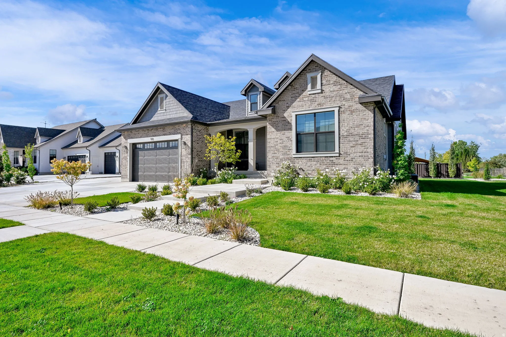 View of front of property with a front yard, concrete driveway, a garage, and brick siding