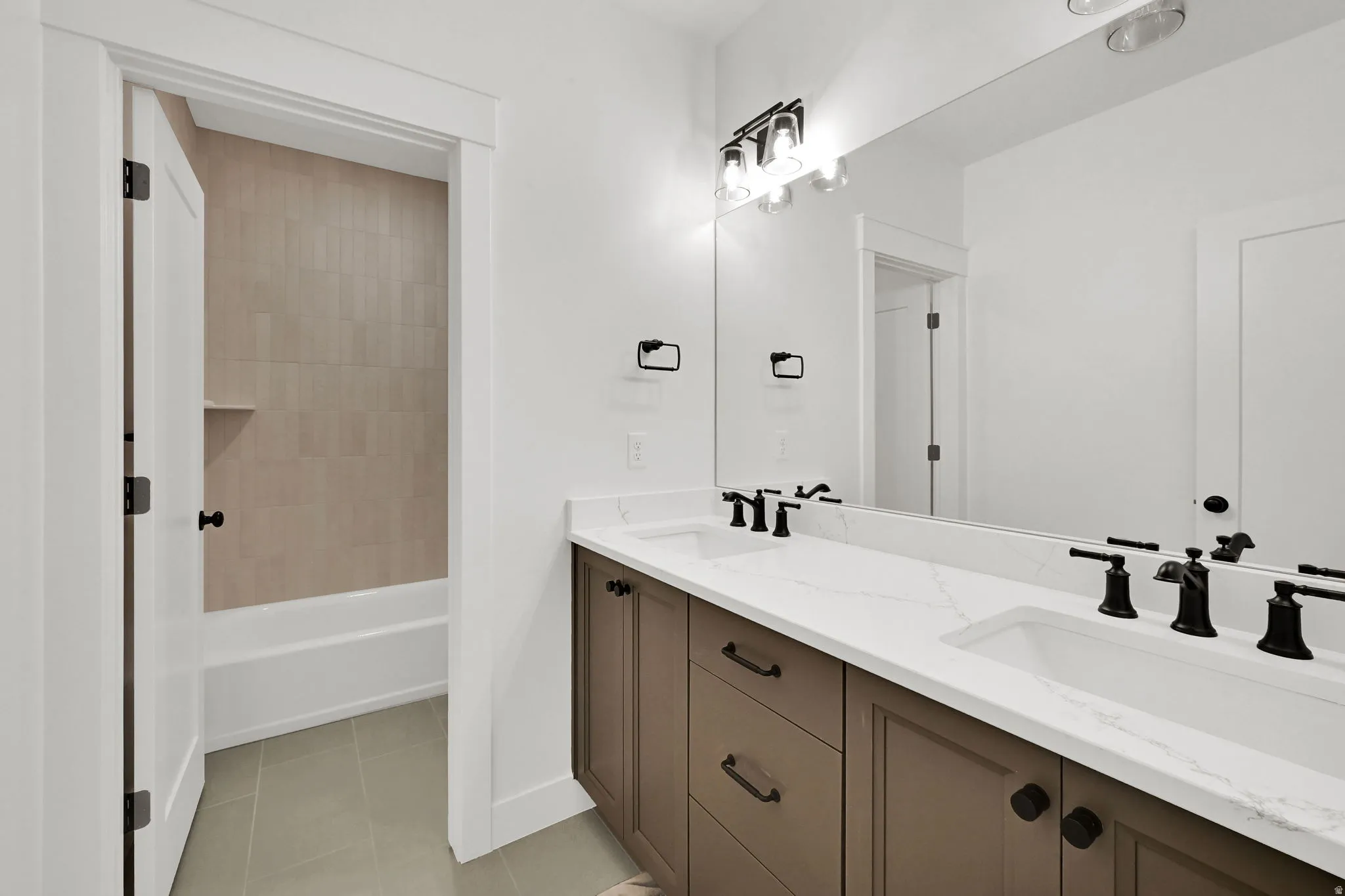 Bathroom featuring double vanity, light tile patterned floors, and shower / tub combination
