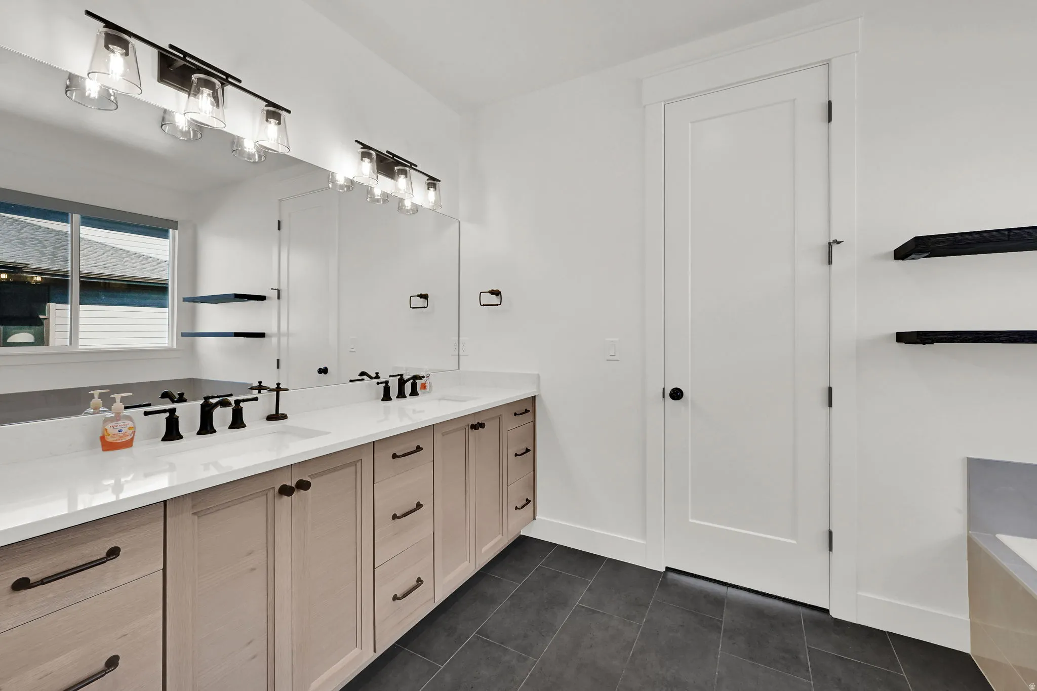 Bathroom with double vanity and dark tile patterned floors