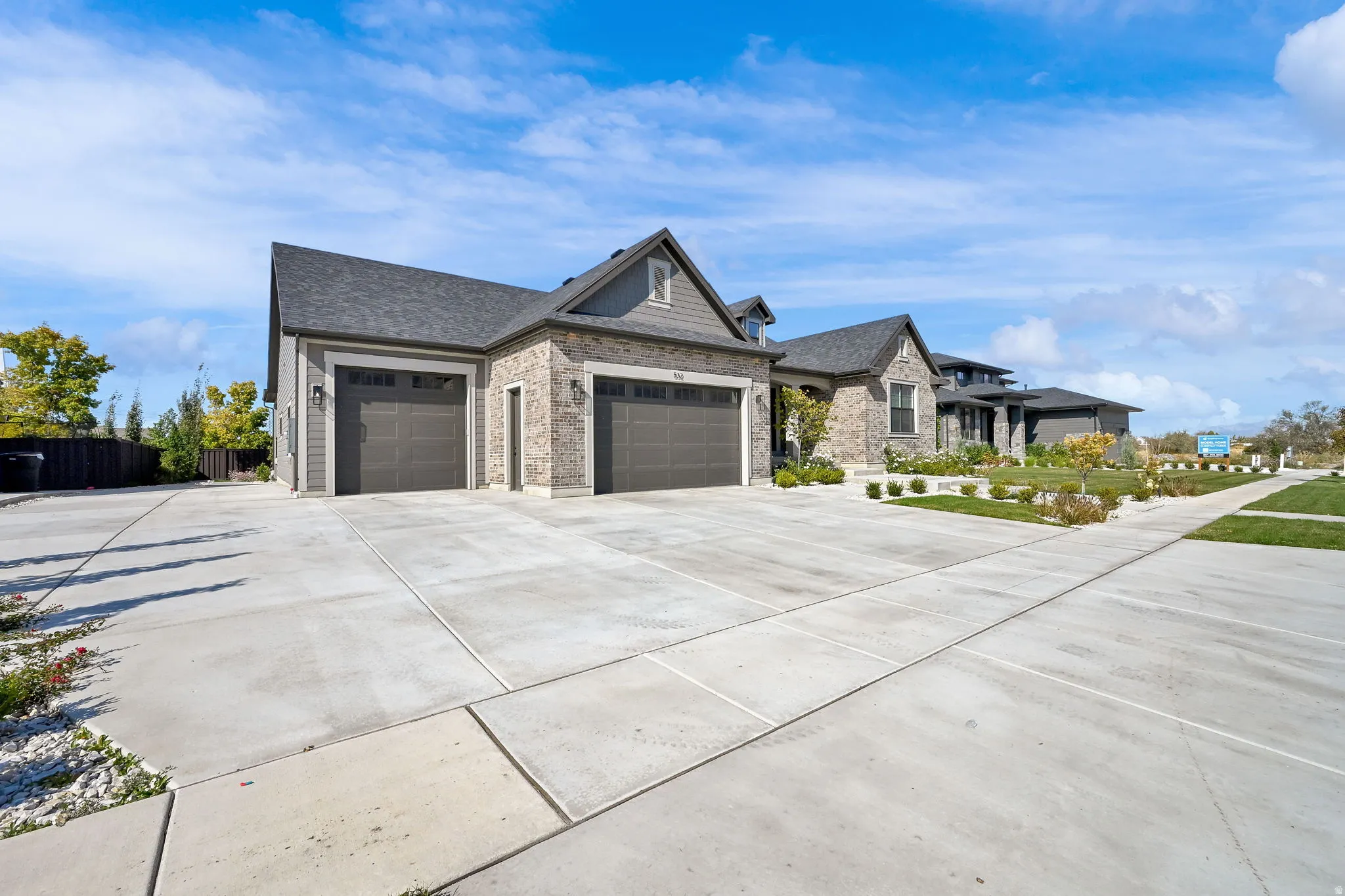 View of front of home featuring a garage, concrete driveway, stone siding, and a shingled roof