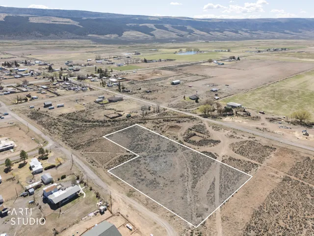 Aerial overview of property's location with rural landscape, property parcel outlined, and a mountainous background