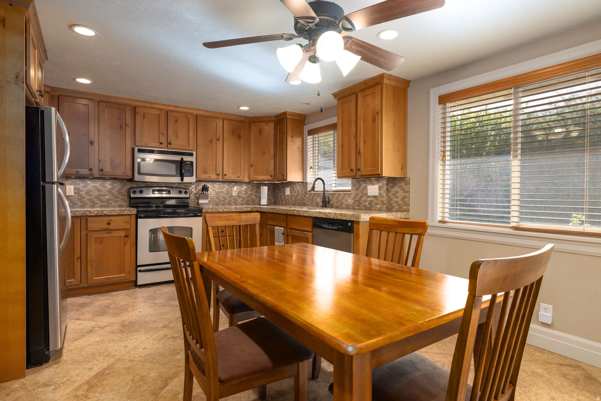 Kitchen with stainless steel appliances, wood finish cabinetry, recessed lighting, a ceiling fan, and tile floors