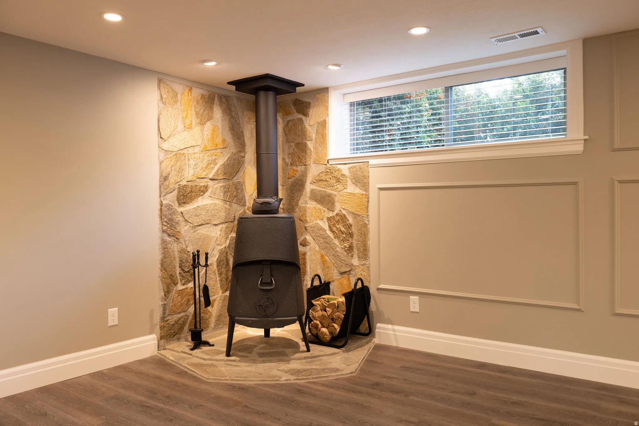 Living area featuring dark wood finished floors, recessed lighting, and a wood stove