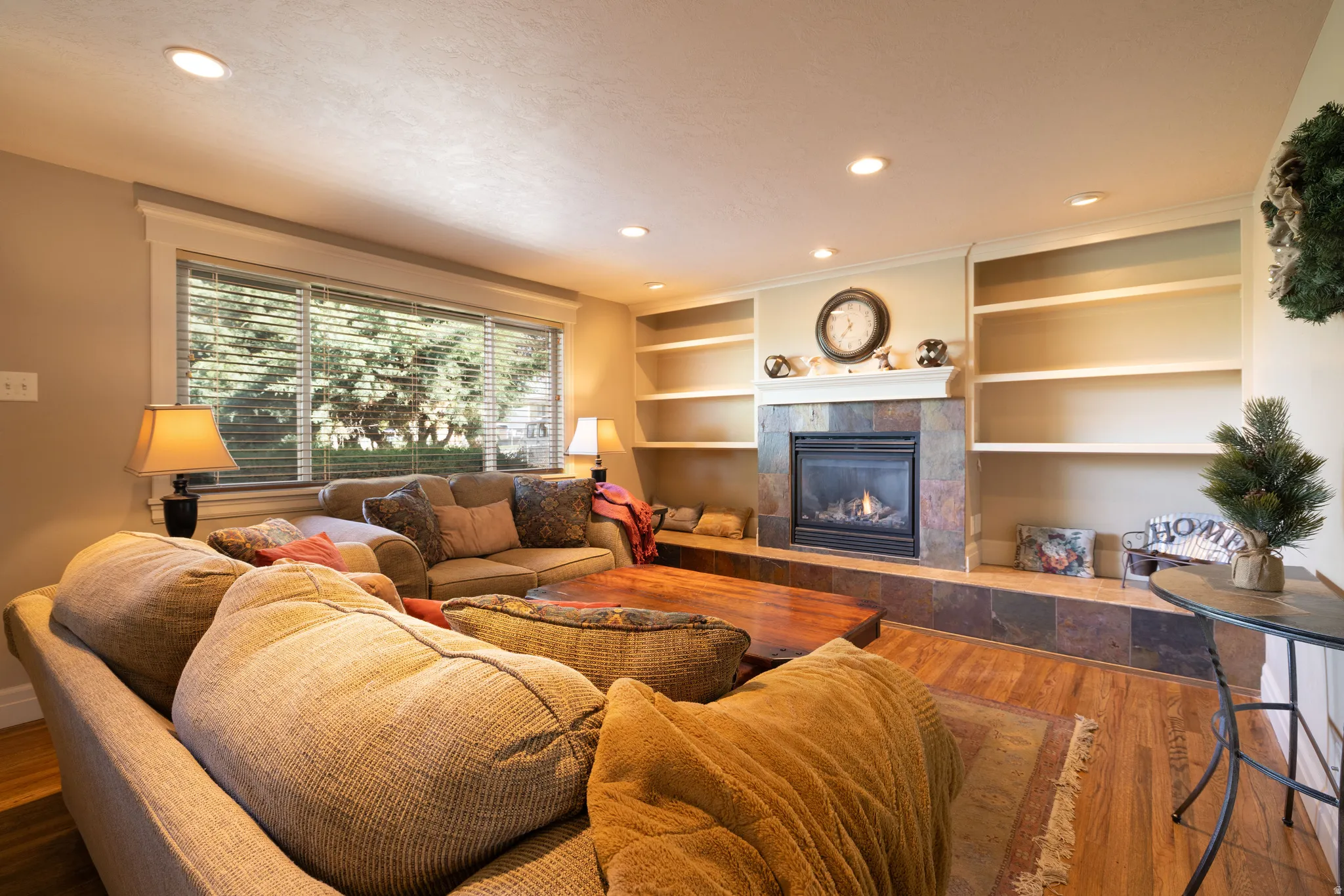 Living room featuring hardwood floors, a fireplace, built in features, and recessed lighting