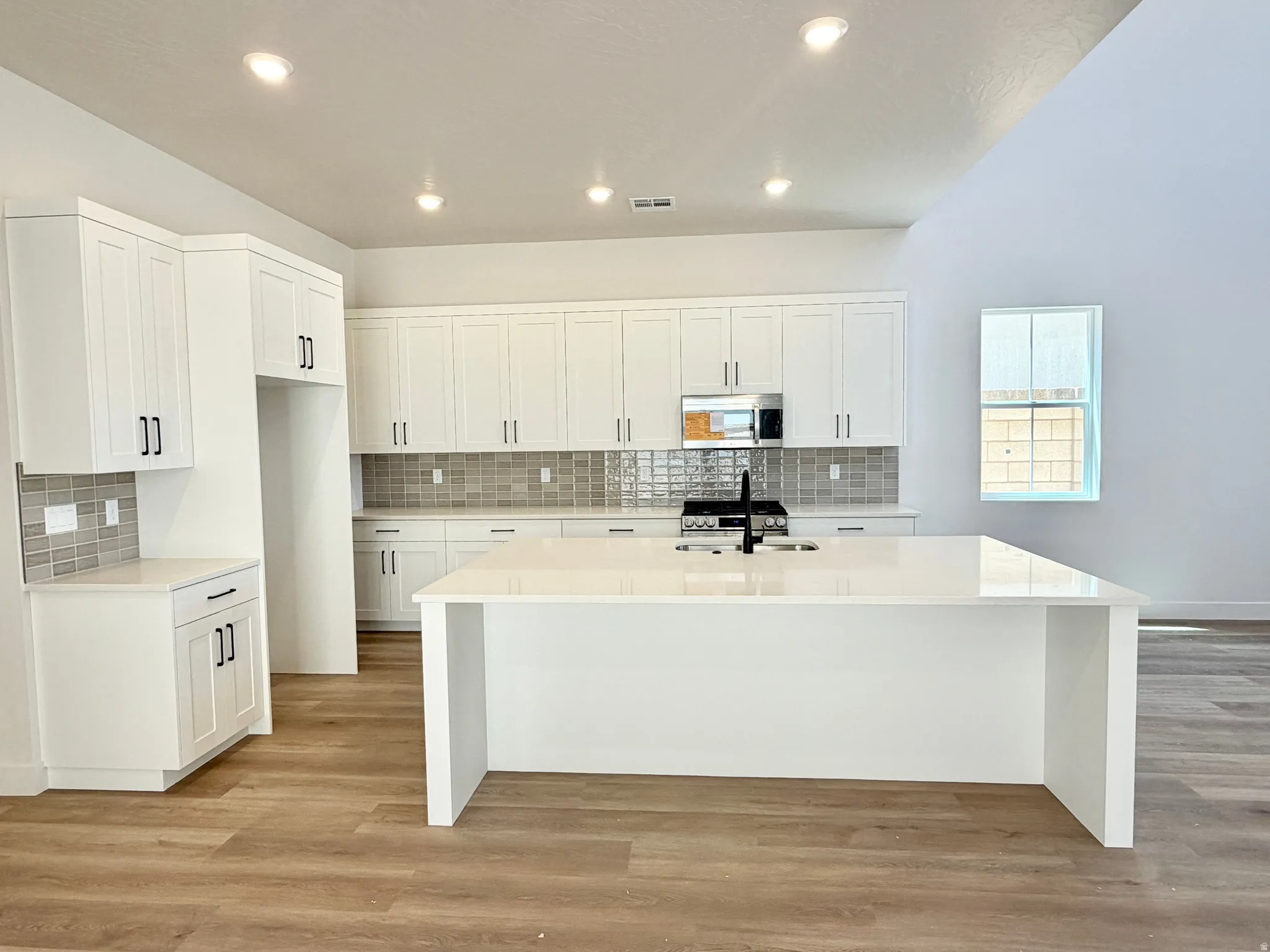 Modern kitchen featuring an expansive island with a white countertop and integrated sink