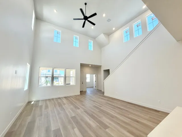 Spacious room featuring vaulted ceilings, wood-finish flooring, a contemporary ceiling fan, recessed lighting, and numerous windows