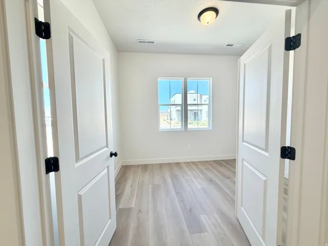 Bright room with wood-finish flooring, white baseboards, and two large windows