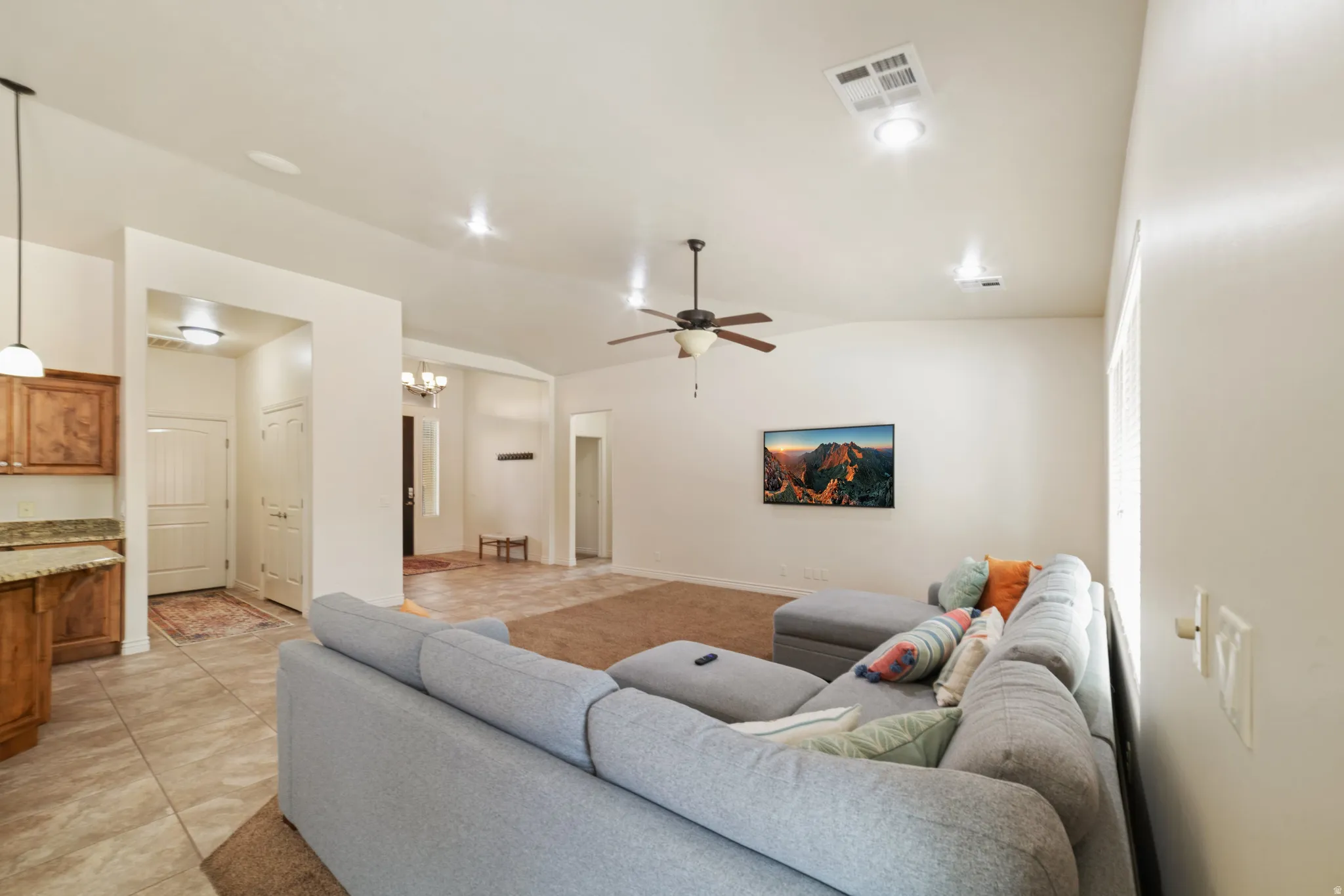 Living area with a ceiling fan, vaulted ceiling, light tile patterned floors, and suspended lighting