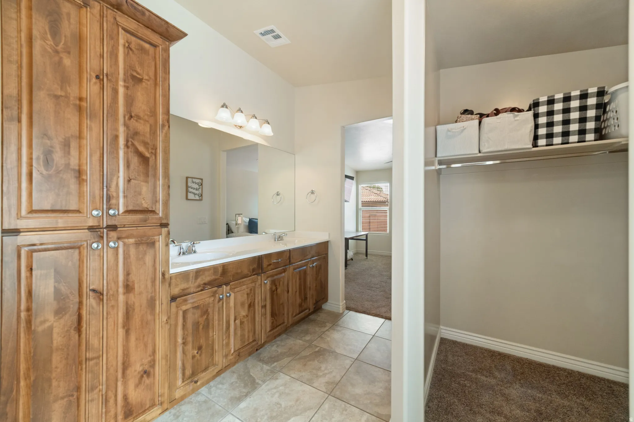 Full bath featuring double vanity, light tile patterned floors, light carpet, and a spacious closet