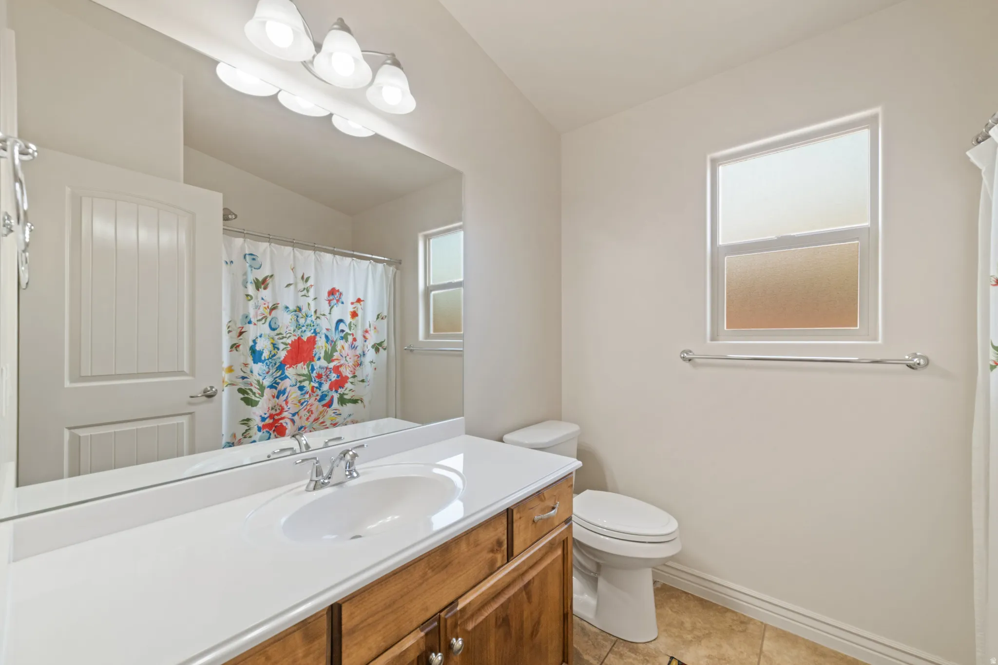 Full bath featuring vanity, lofted ceiling, light tile patterned flooring, and curtained shower