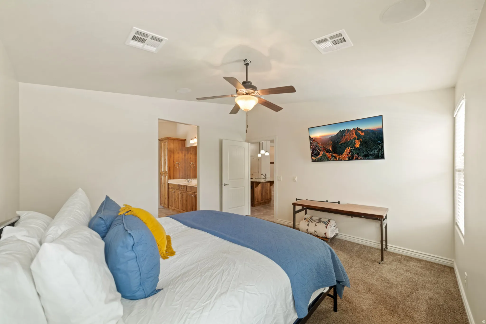 Carpeted bedroom with ensuite bath and ceiling fan