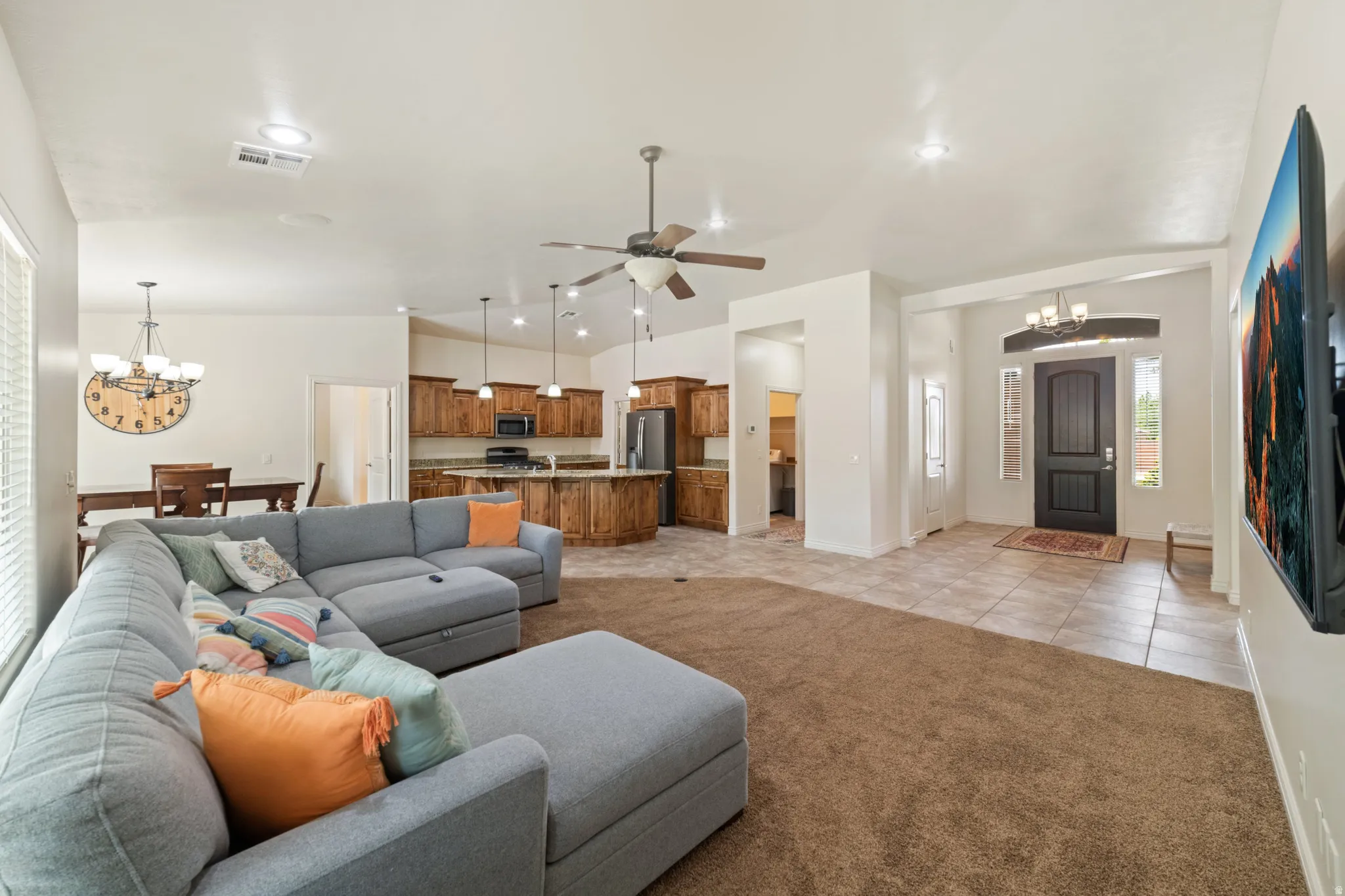 Living area with hanging lights, light carpet, lofted ceiling, a ceiling fan, and light tile patterned floors