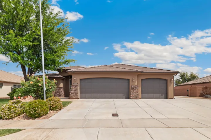 View of front of property with stucco siding, a tiled roof, stone siding, a garage, and driveway