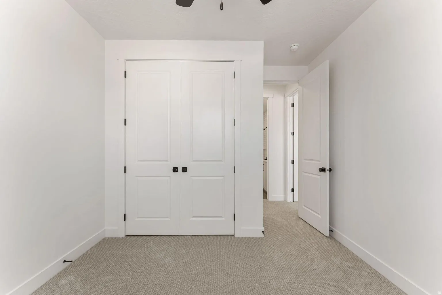 Unfurnished bedroom with light carpet, a closet, and a ceiling fan