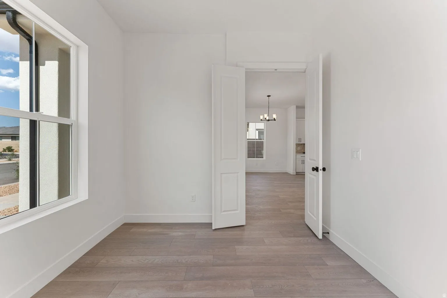 Empty room with light wood-type flooring and a chandelier