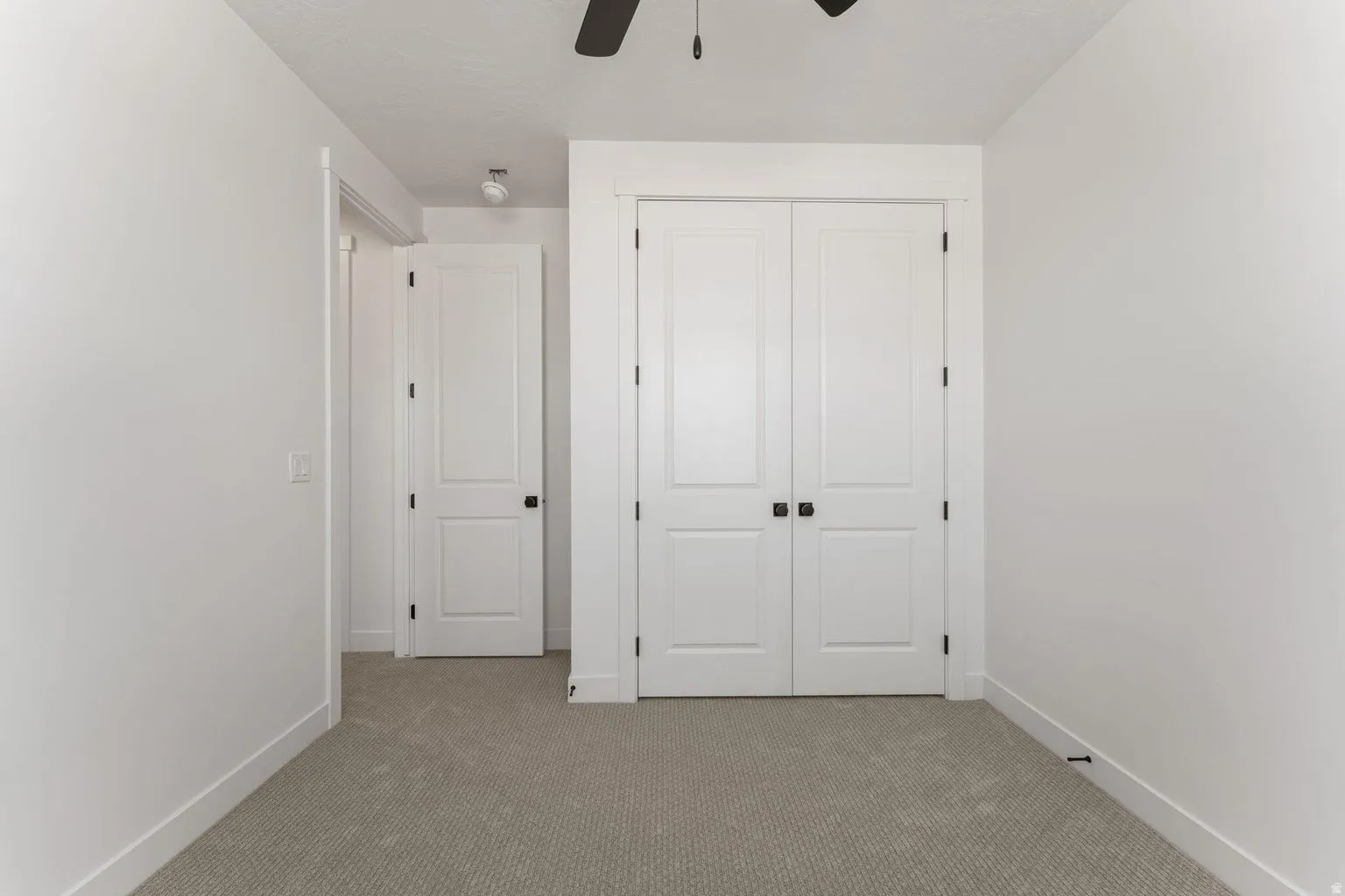Unfurnished bedroom featuring light colored carpet, a closet, and a ceiling fan