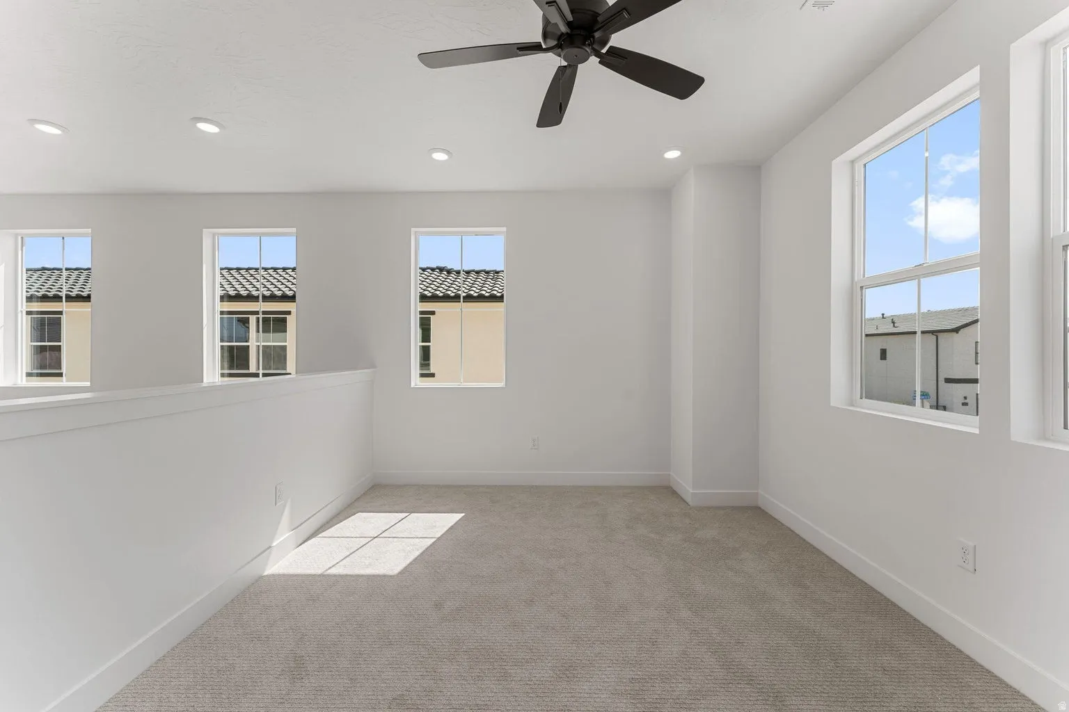 Empty room with ceiling fan, light carpet, plenty of natural light, and recessed lighting