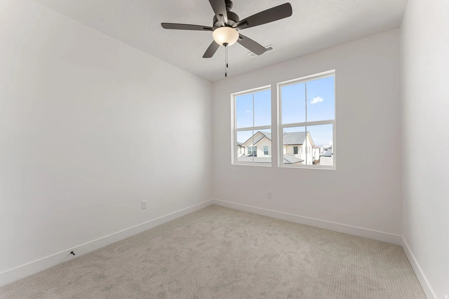 Empty room featuring light colored carpet and ceiling fan