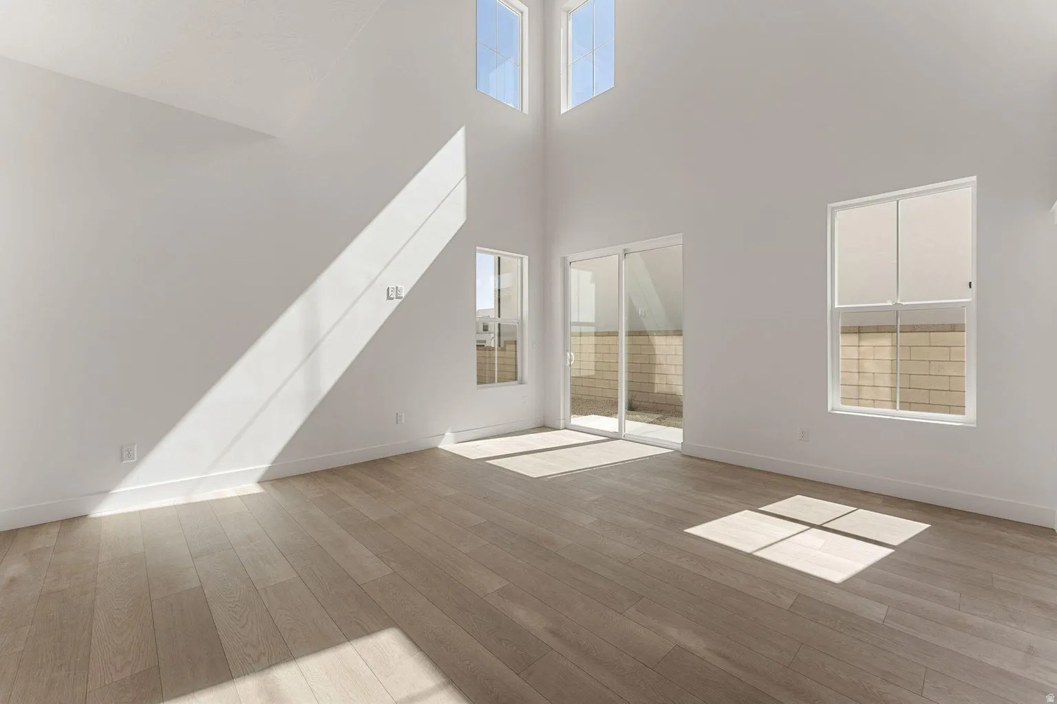 Unfurnished living room with light wood finished floors and a high ceiling
