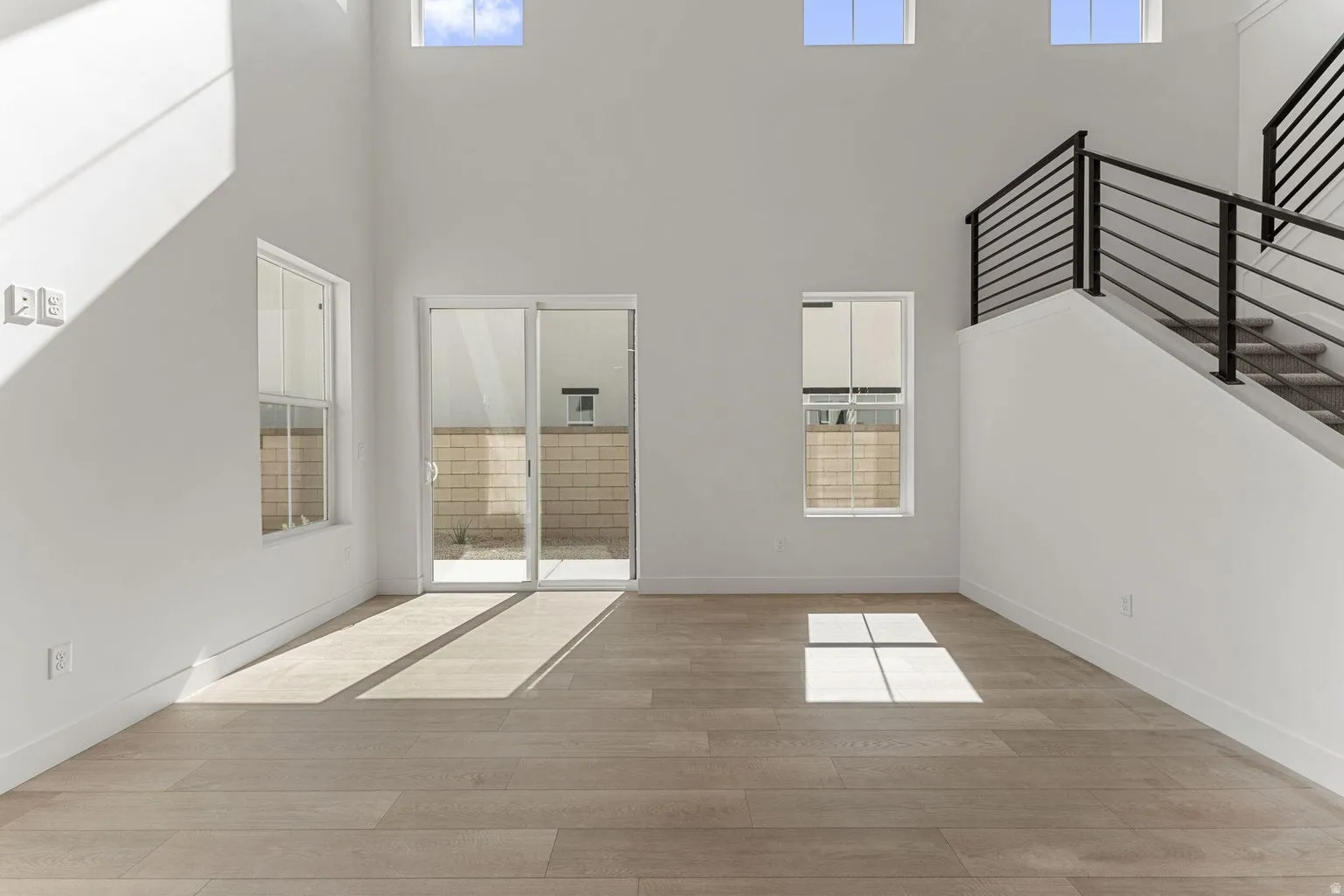 Unfurnished living room with light wood-type flooring, plenty of natural light, and a high ceiling