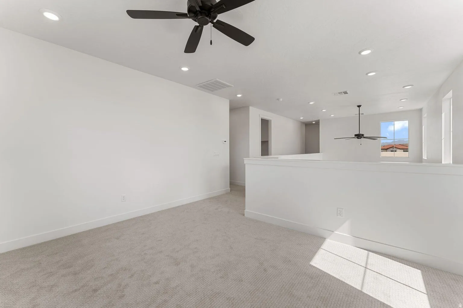 Empty room featuring ceiling fan, light carpet, and recessed lighting