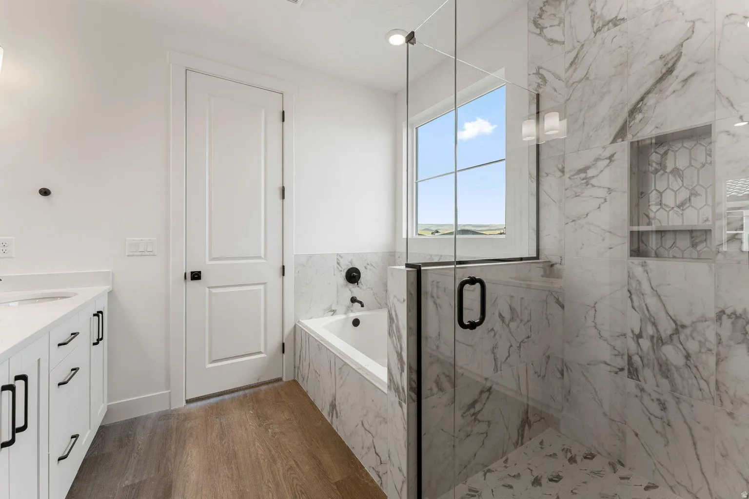 Full bath with vanity, a bath, a marble finish shower, and dark wood finished floors