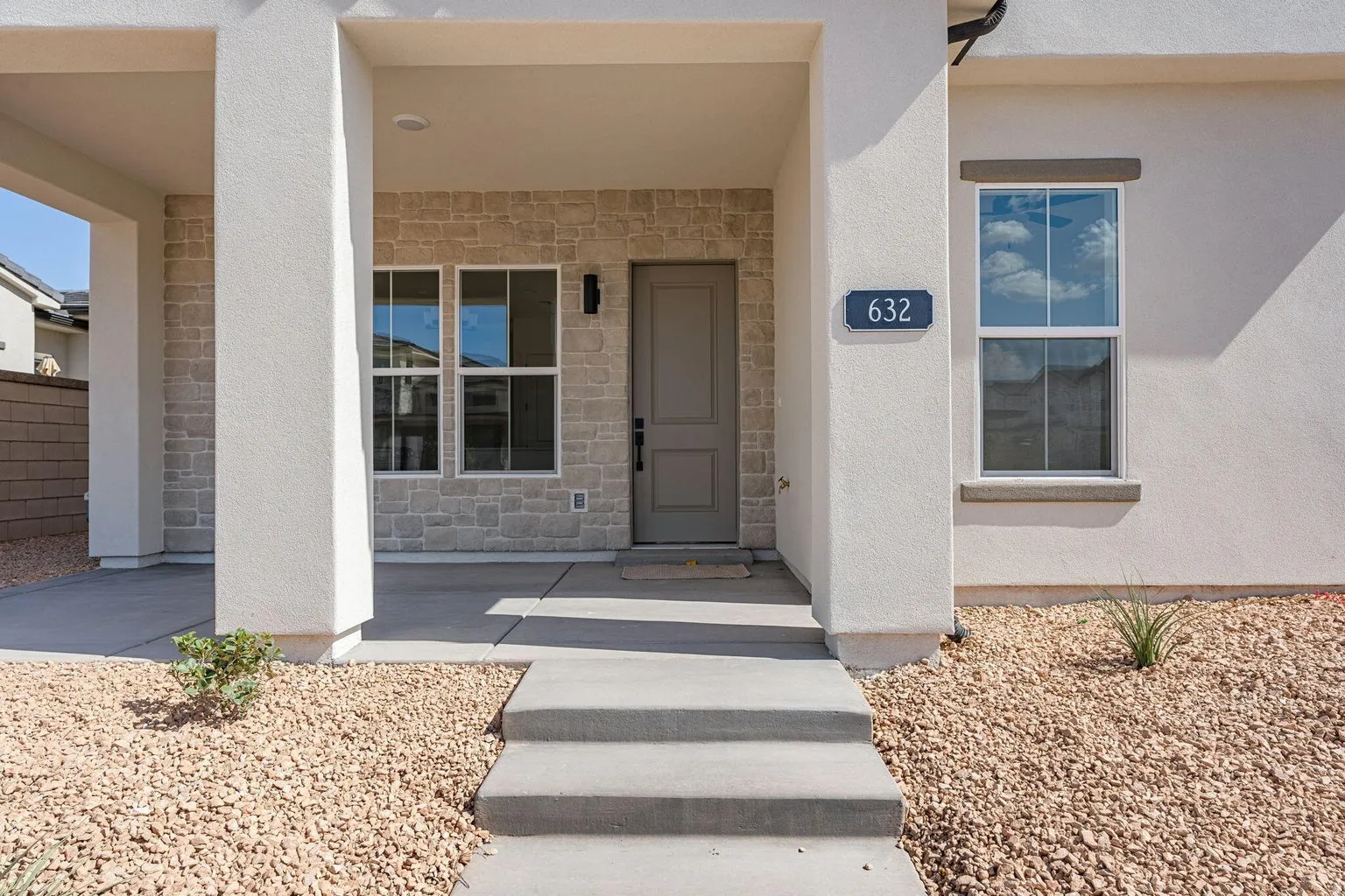 View of exterior entry with stone siding, stucco siding, and a porch