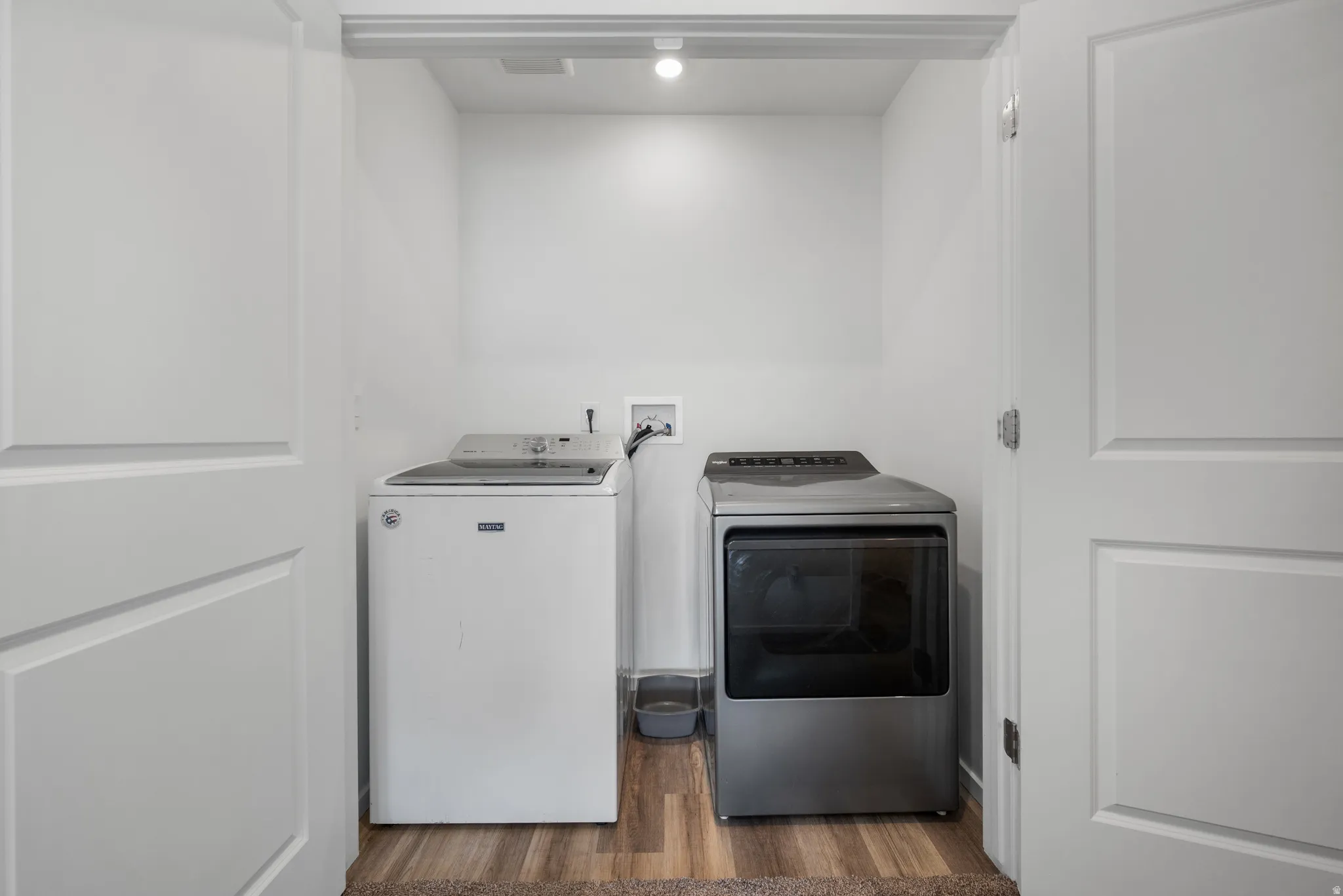 Laundry area with dark wood finished floors and washing machine and clothes dryer