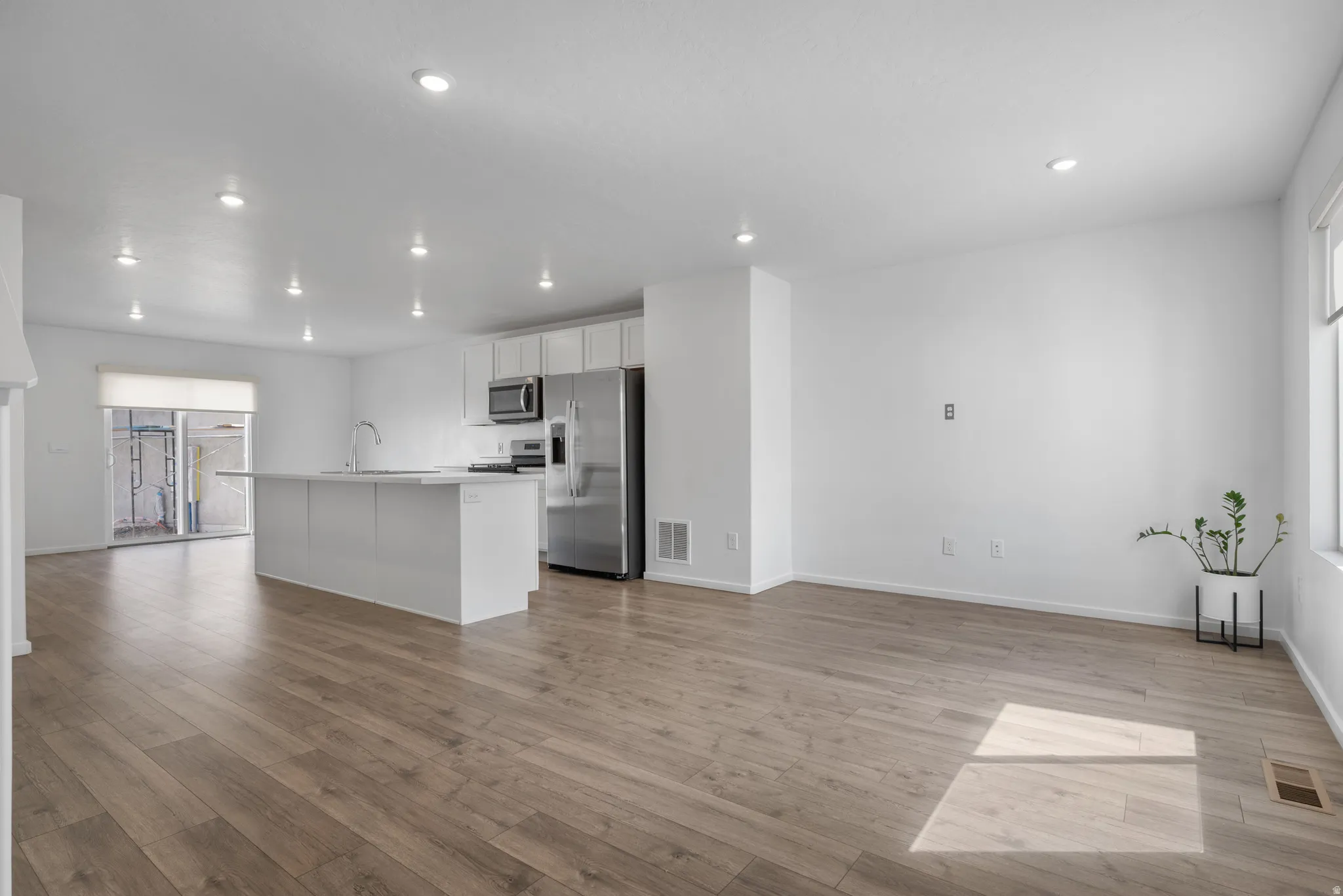 Kitchen with healthy amount of natural light, stainless steel appliances, light countertops, an island with sink, and recessed lighting