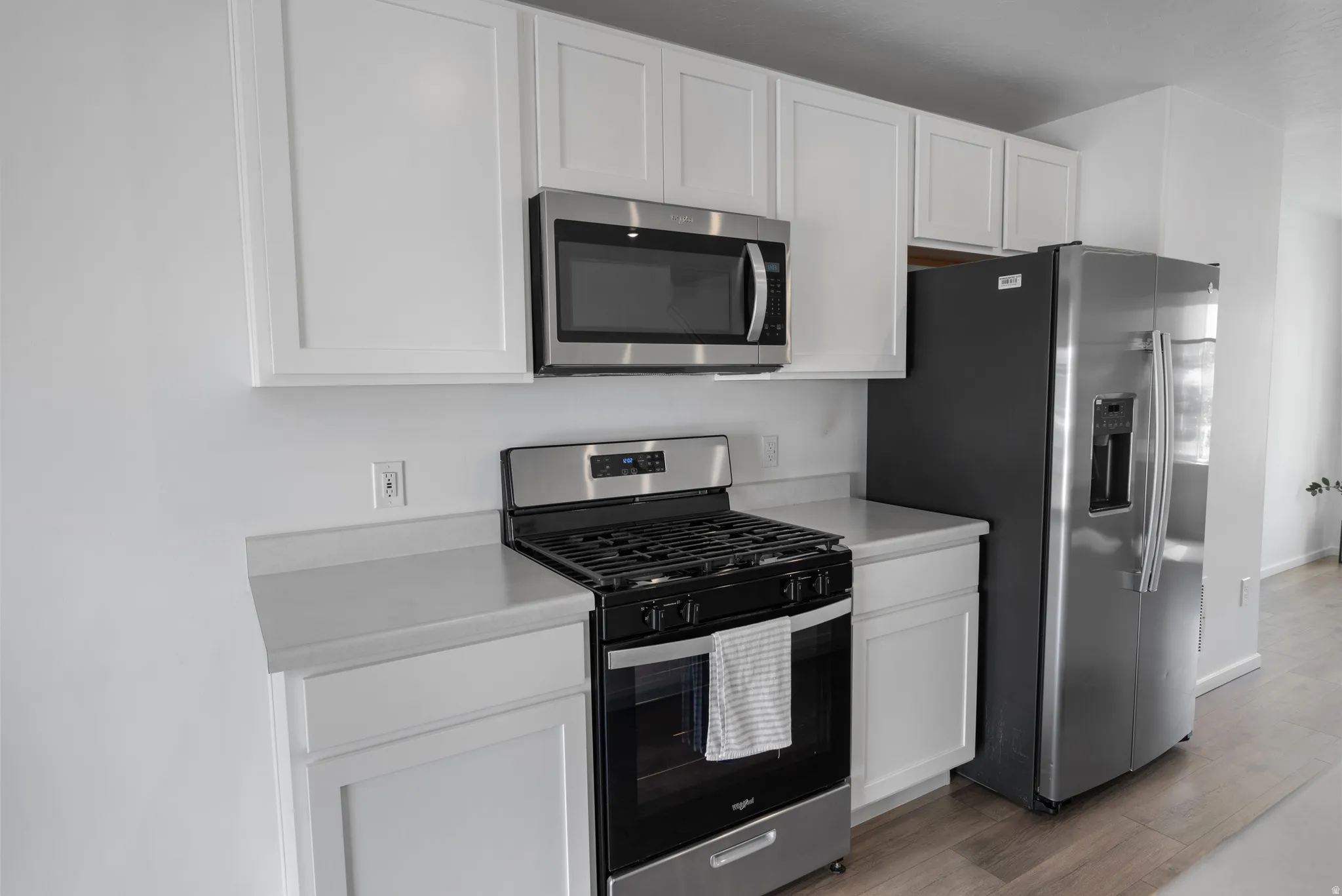 Kitchen with stainless steel appliances, light countertops, and white cabinetry