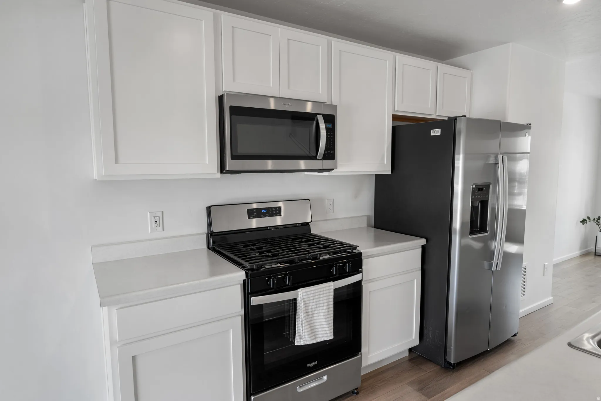 Kitchen with stainless steel appliances, light countertops, and white cabinets