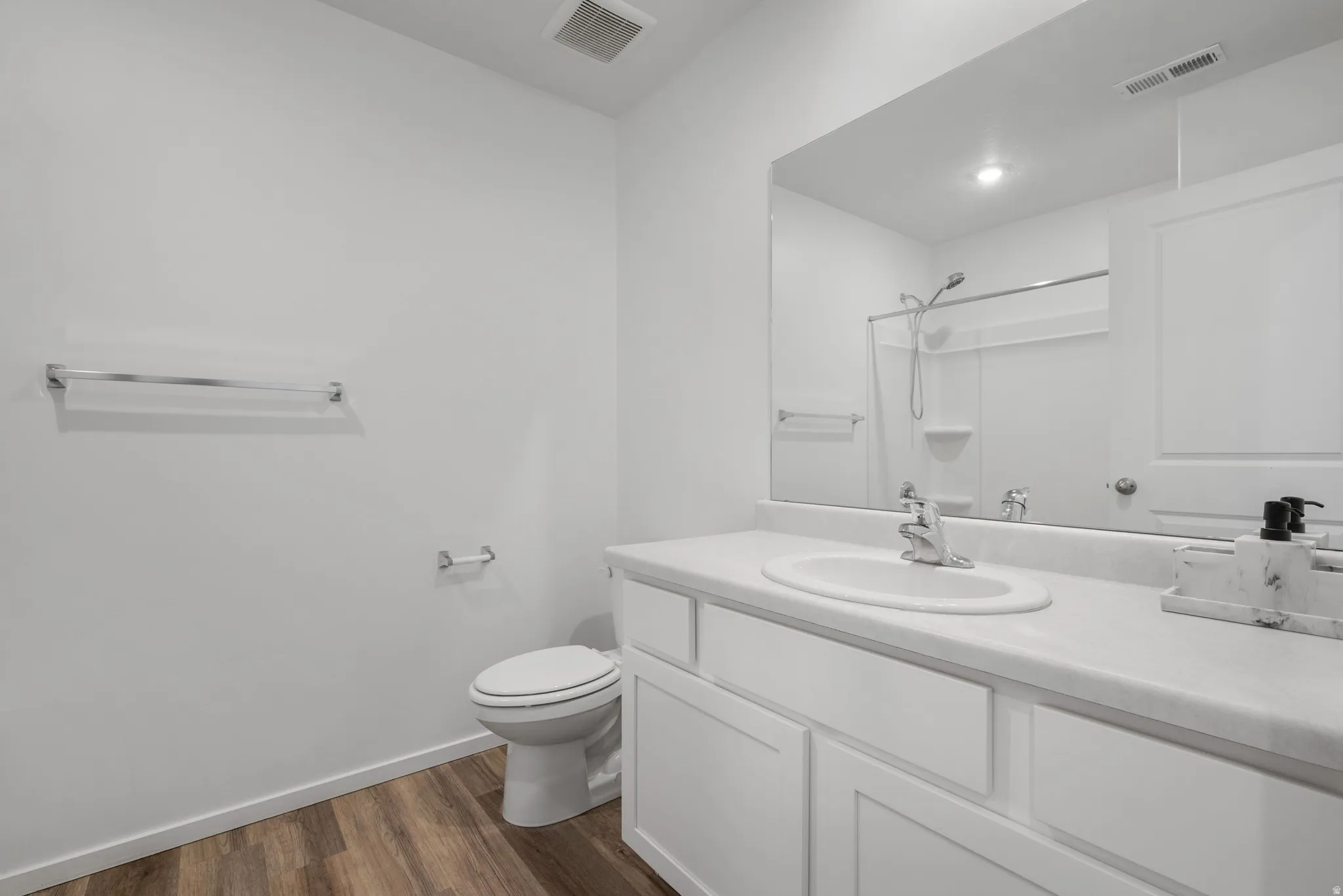 Full bathroom featuring vanity, dark wood finished floors, and a shower