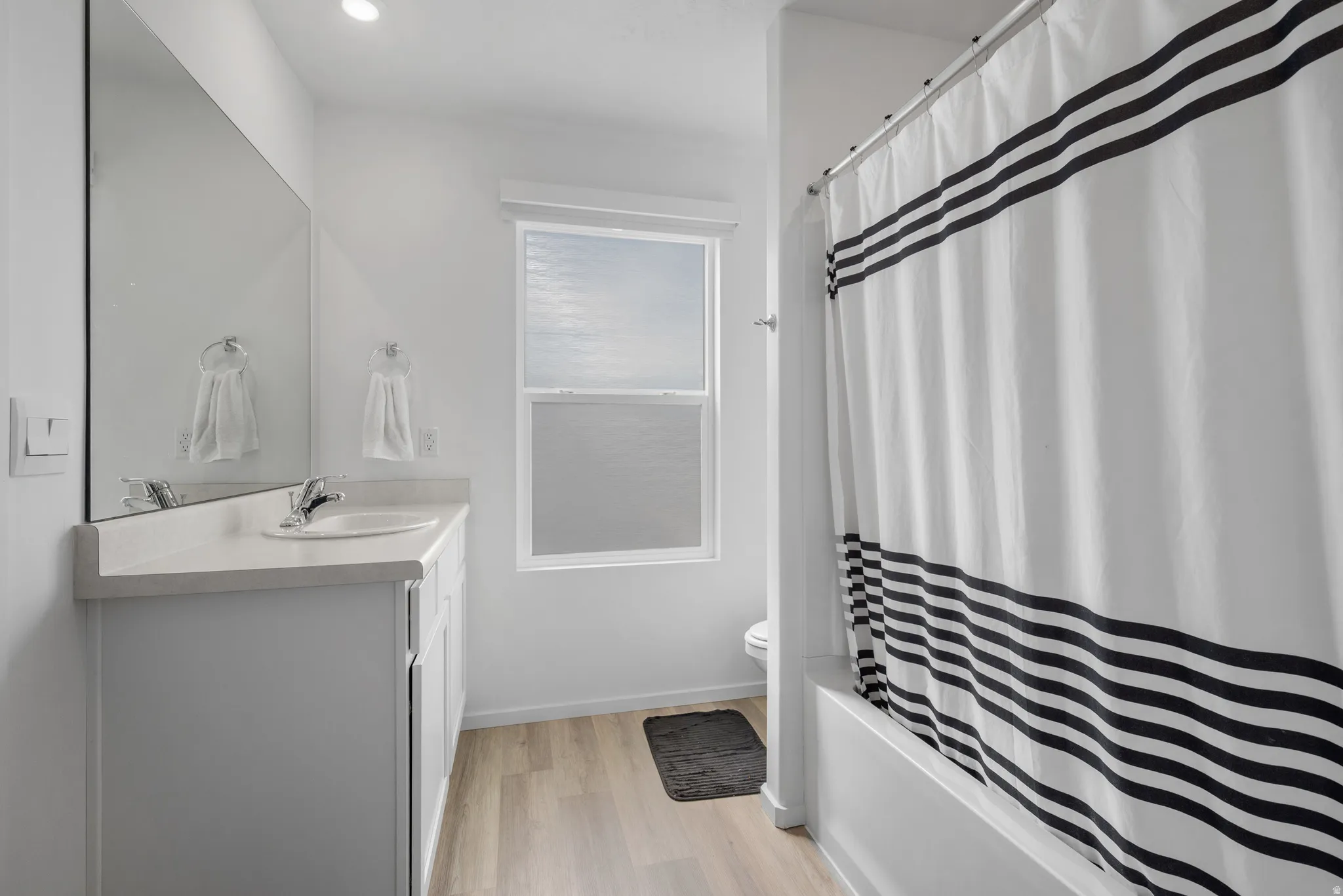 Full bathroom featuring vanity, light wood finished floors, and shower / bath combination with curtain